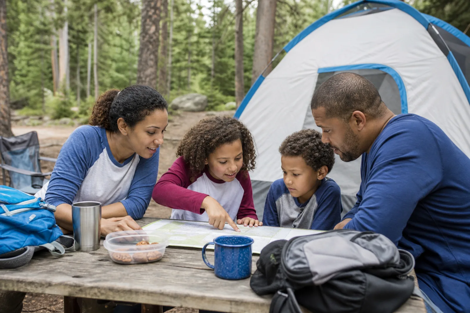 A family studies a campground map together beside their tent.